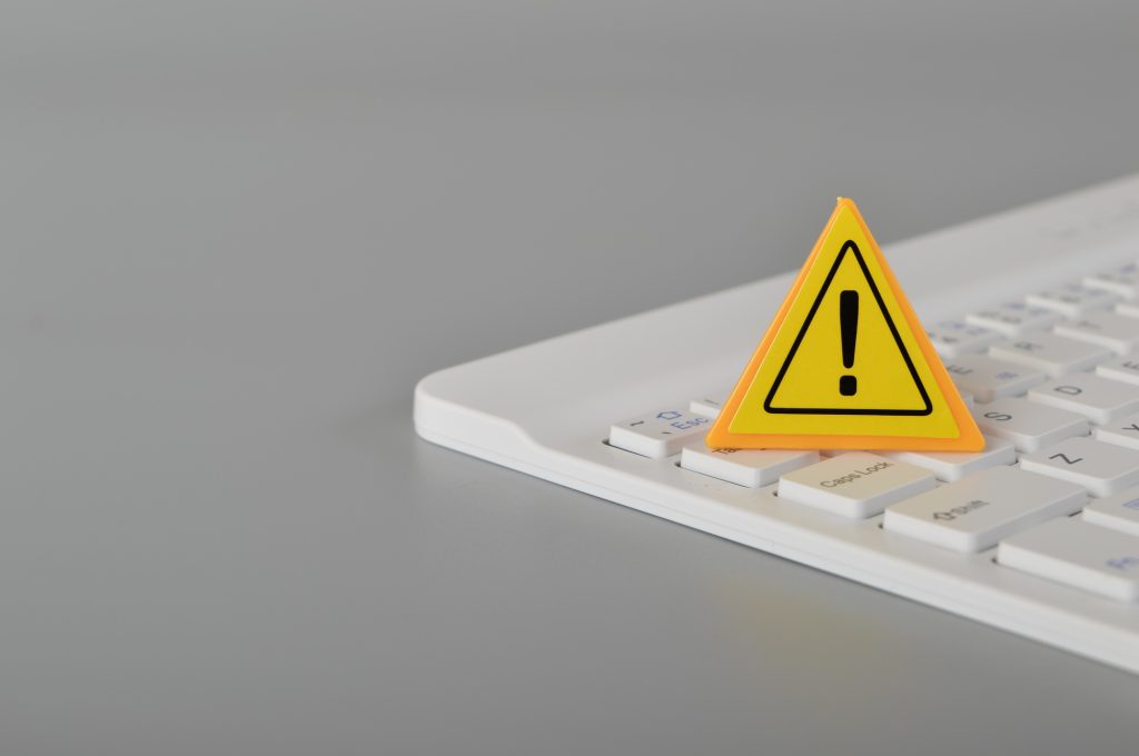 Computer keyboard and warning sign. Data thief, internet fraud, cyber security concept.